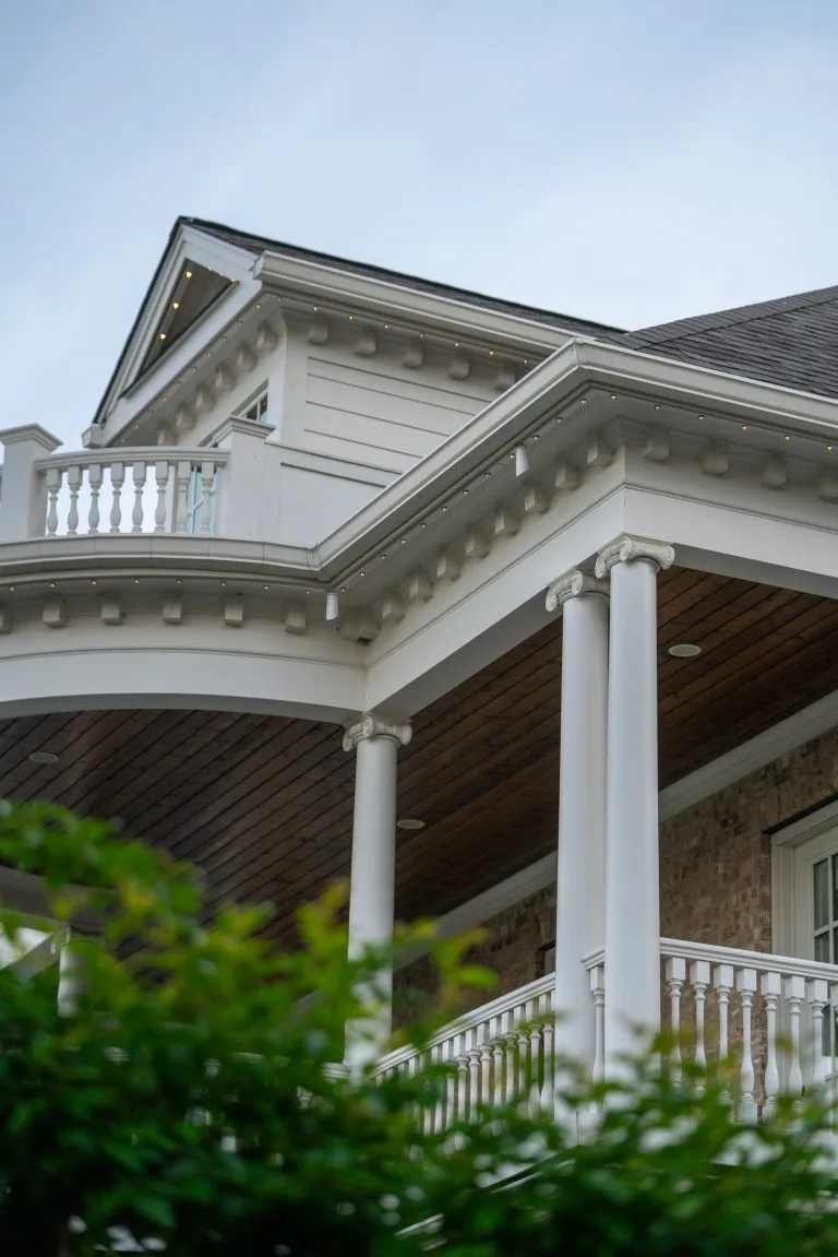 A stylish house features a covered porch with decorative columns and balcony