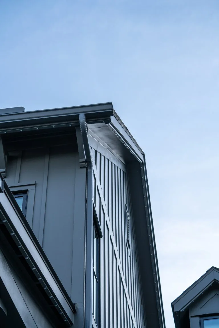 A modern building features a sharp, angular roof against a clear blue sky