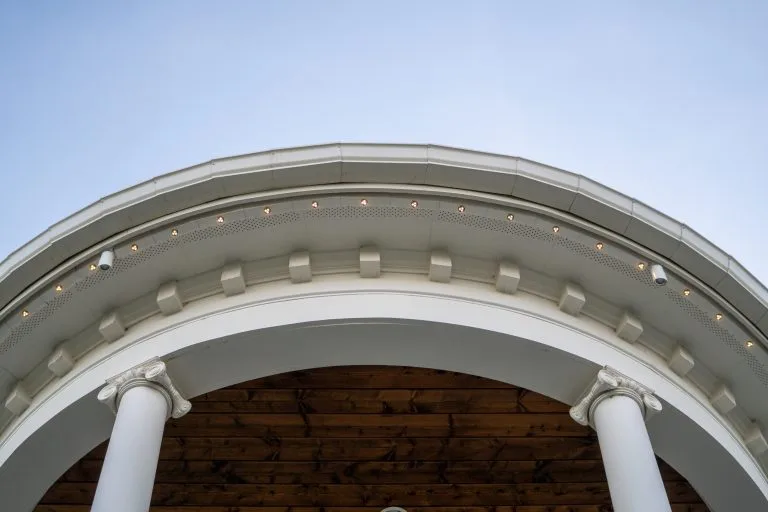 A curved, white architectural structure showcases columns against a clear blue sky
