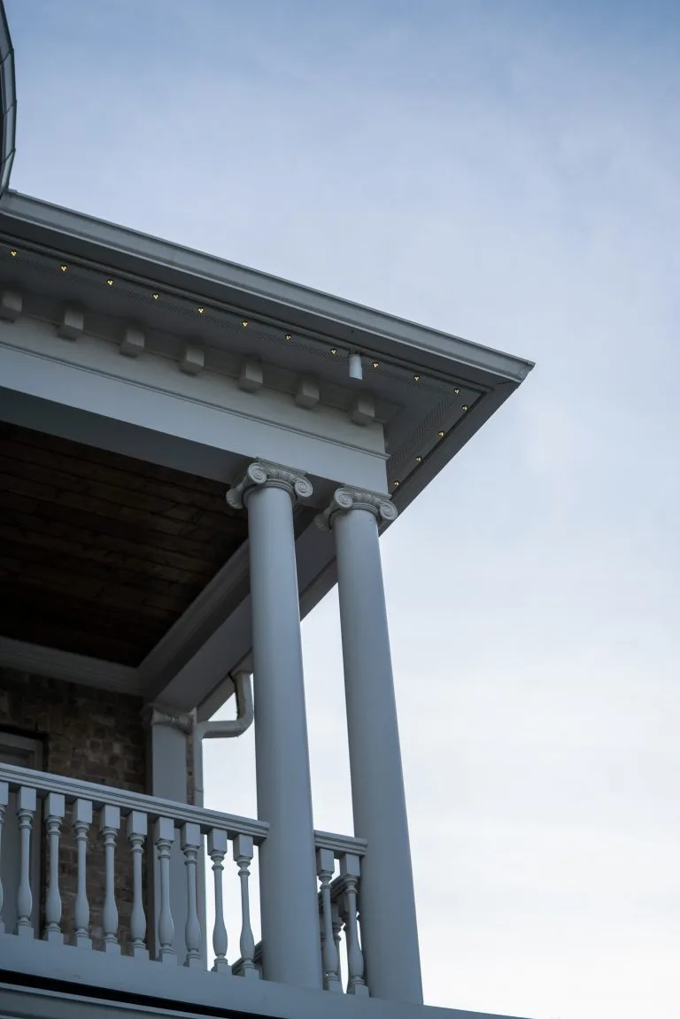 A building's elegant porch features decorative columns under a clear sky