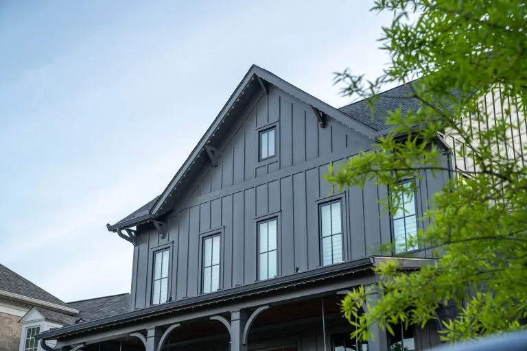 A modern gray house features multiple windows against a clear sky