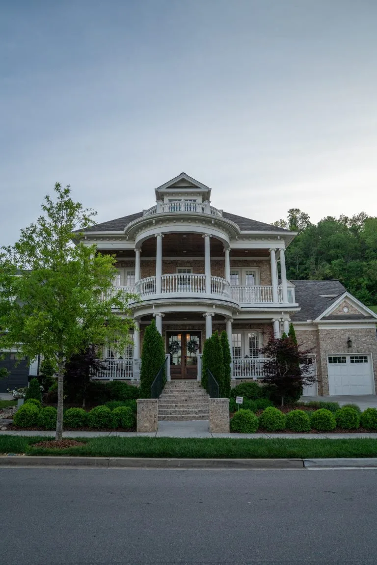 A grand, multi-level house features elegant balconies and well-maintained landscaping