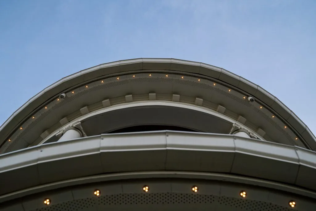 A low-angle view captures architectural curves under a clear blue sky