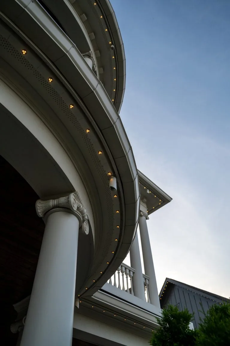 A grand building features elegant columns and a curving balcony under a clear sky