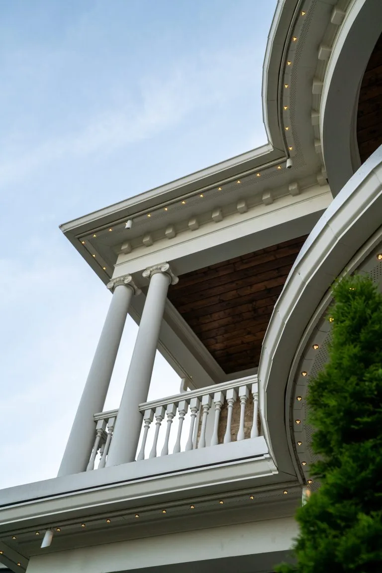 A grand building features elegant columns and a balcony under a vast sky