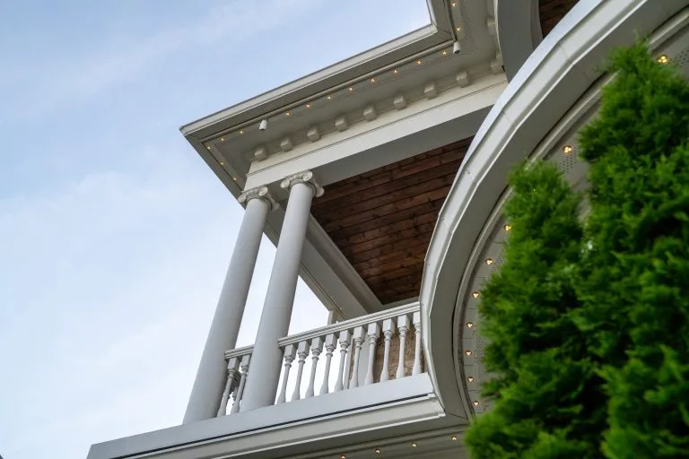 A grand building features elegant columns and a curved balcony, under a clear sky