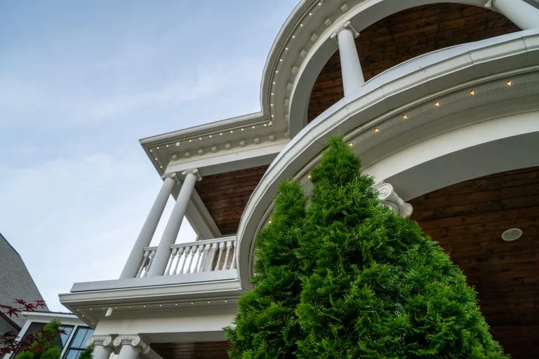 A grand architectural structure features curved balconies and decorative columns against a cloudy sky
