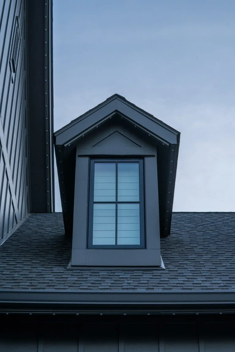 A gable roof features a prominent window against a cloudy sky