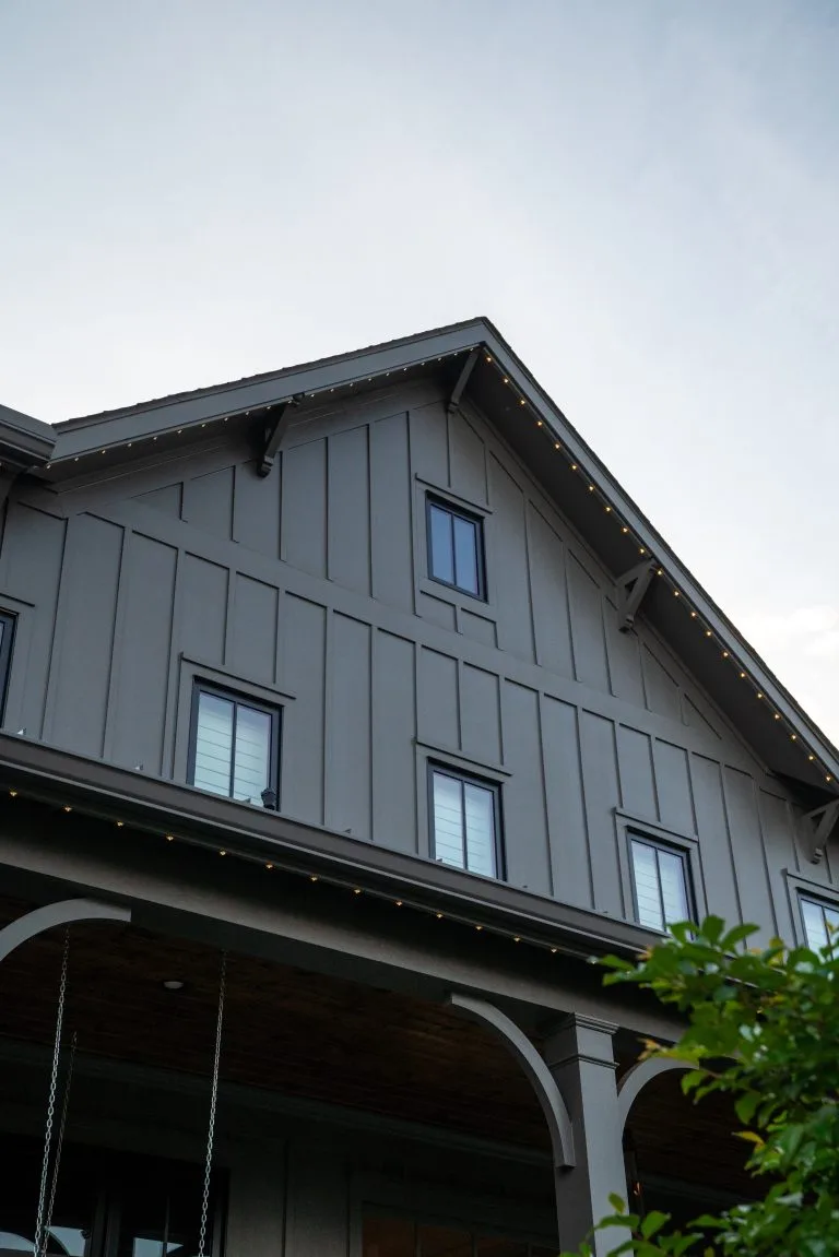 A gray, modern house features symmetrical windows beneath a soft sky
