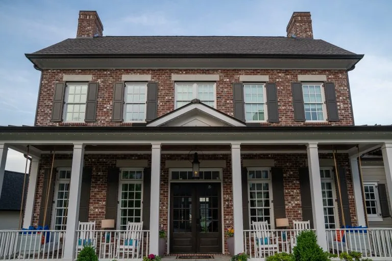 A charming brick house features a welcoming porch adorned with rocking chairs