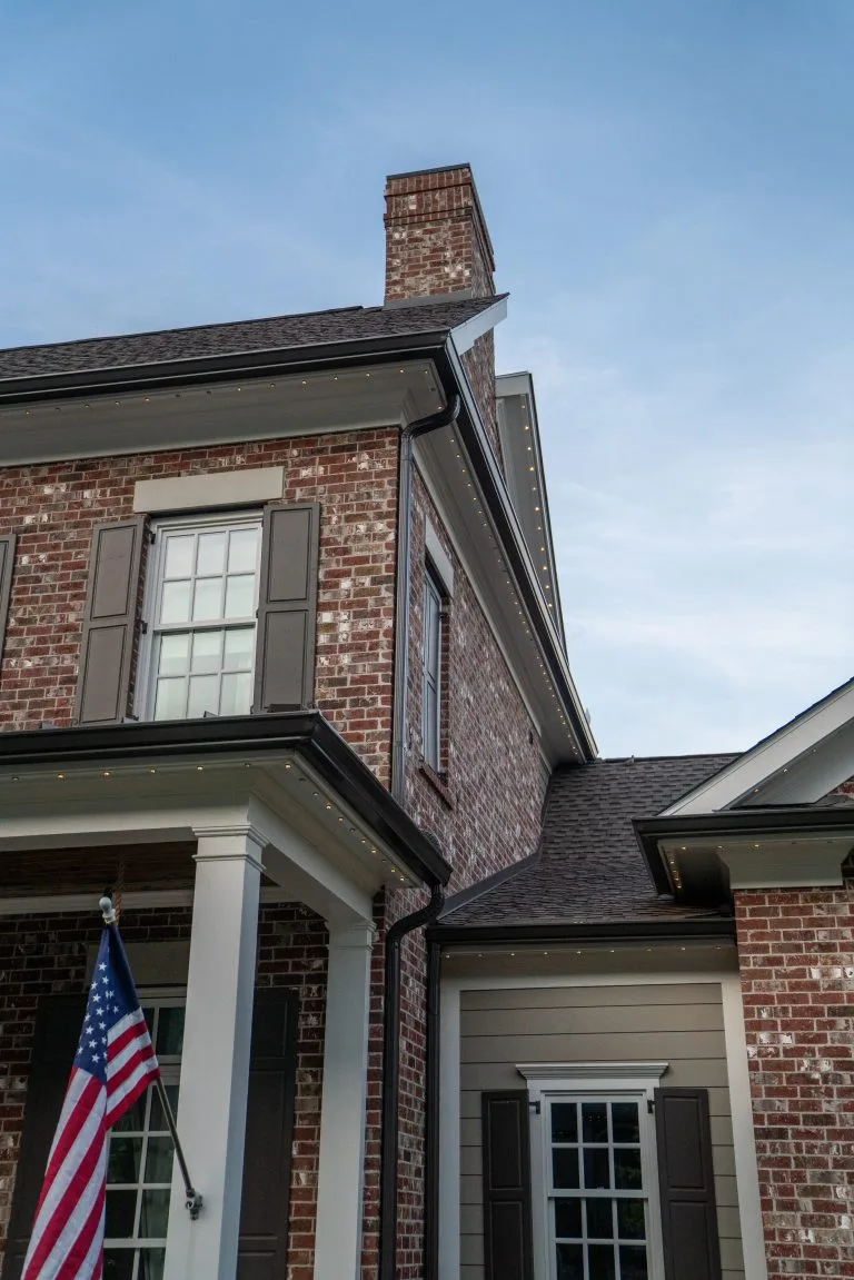 A brick house features a chimney and an American flag hanging outside
