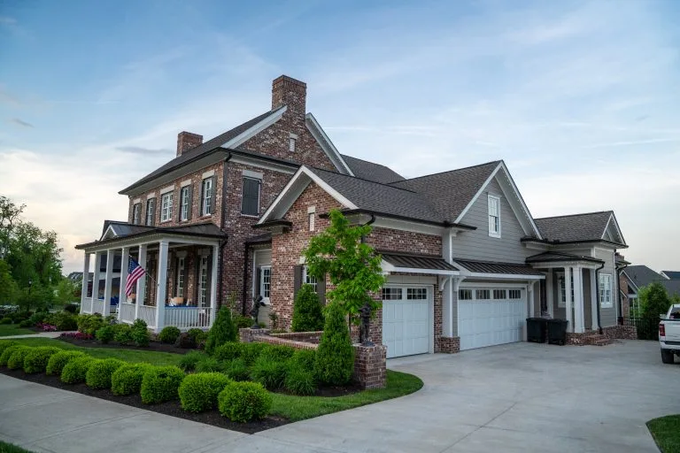 A large brick house with a manicured lawn and a parked vehicle