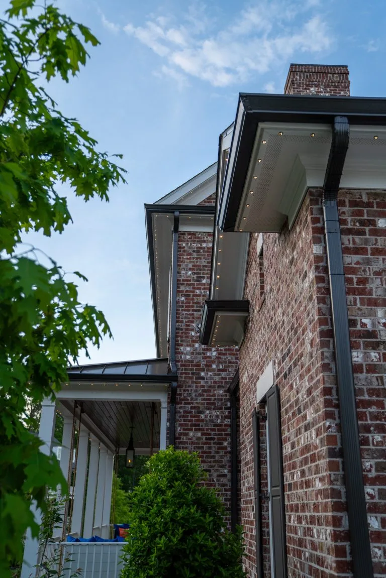 A brick house with a modern roof contrasts against a clear blue sky