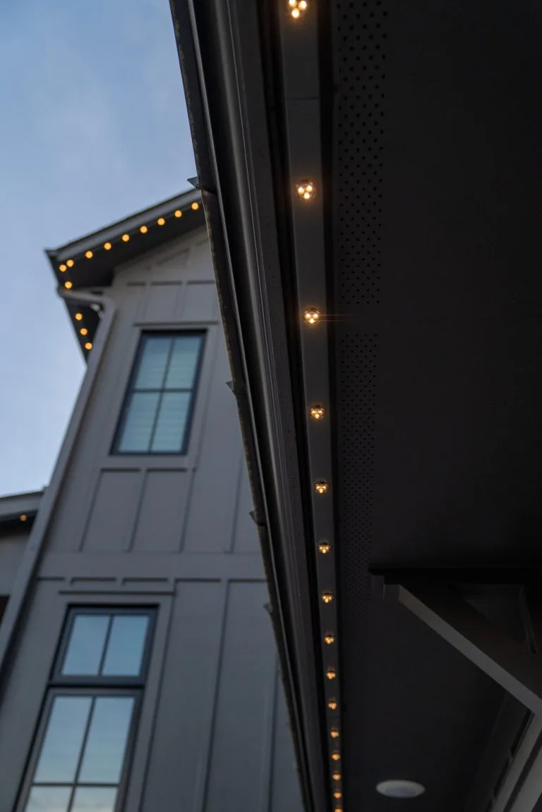 Warm lights outline the eaves of a modern, stylish building against a twilight sky