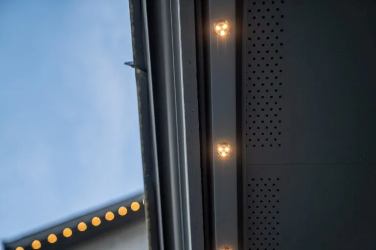 Warm lights illuminate the edge of a building against a clear sky