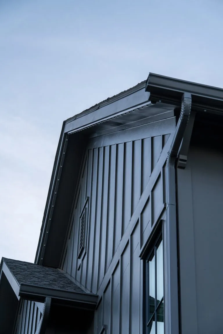 A modern house features a sleek, angled roof against a blue sky