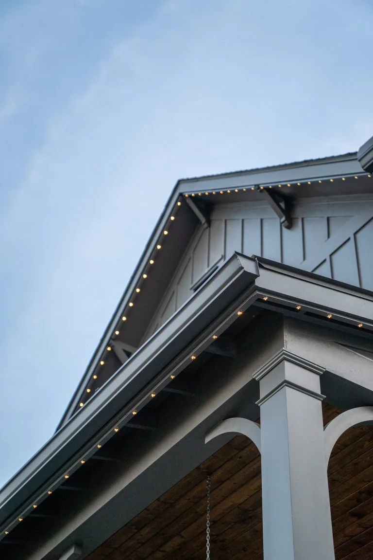 A house features intricate architecture with subtle lighting along the eaves against a blue sky