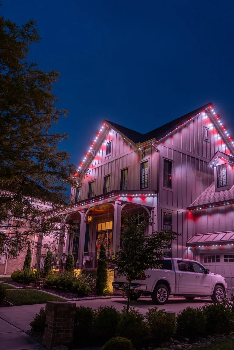 A beautifully decorated house gleams with festive lights against a twilight sky
