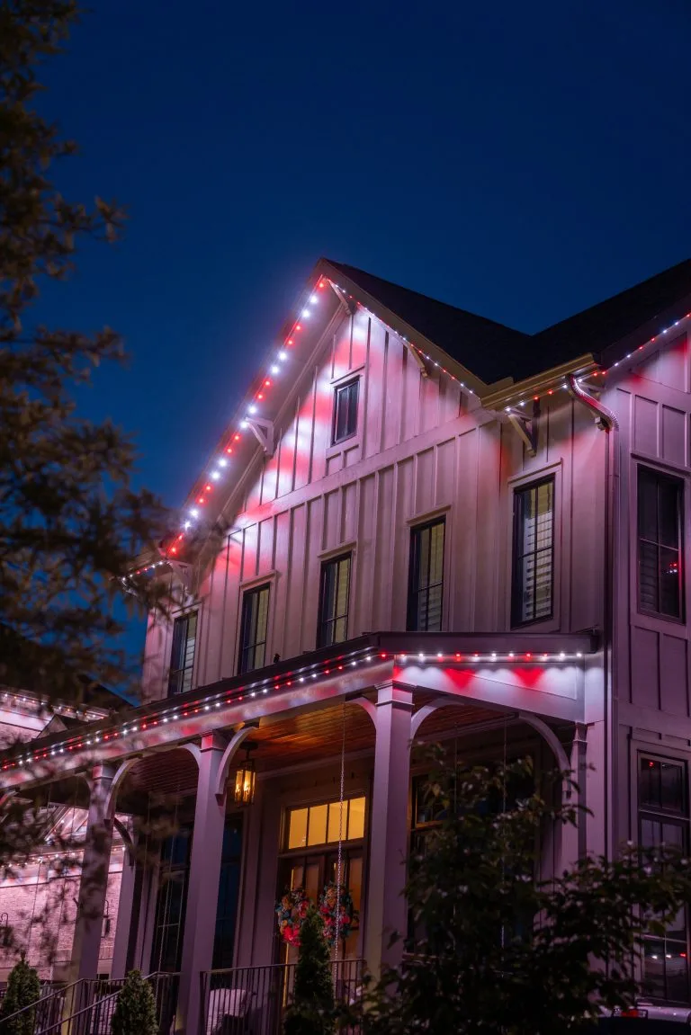 A brightly lit house shines with colorful lights against a night sky