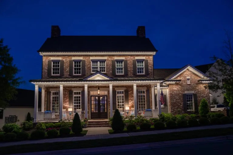A beautifully lit brick house showcases its architectural details at twilight