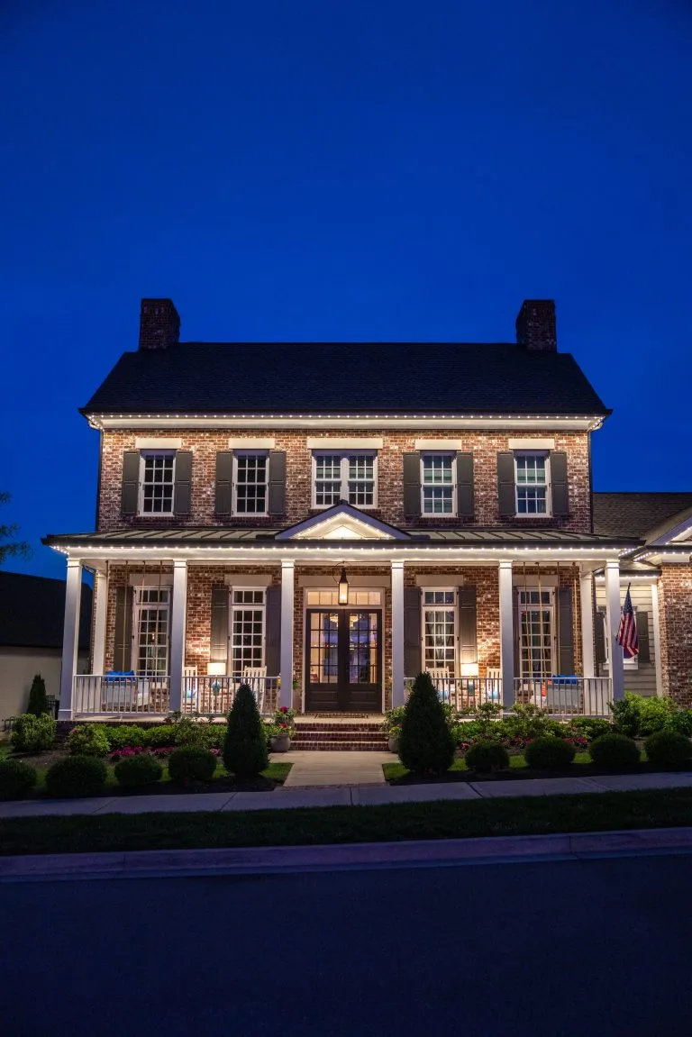 A beautifully illuminated brick house stands against a deep blue evening sky