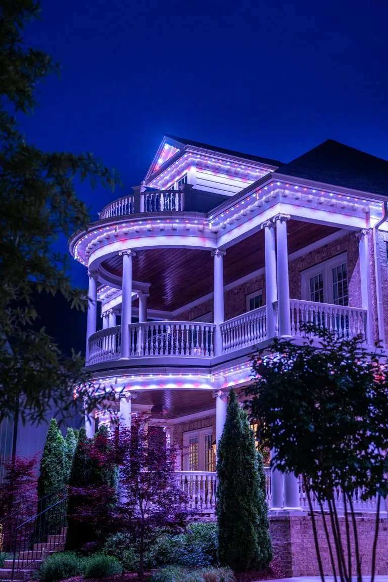A beautifully lit house adorned with colorful lights glows against the night sky