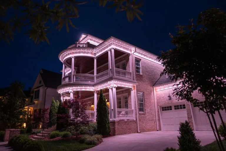 A beautifully illuminated house features elegant architecture amidst a nighttime backdrop