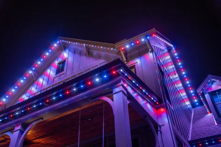 Bright, colorful lights adorn the edges of a house against a dark night sky