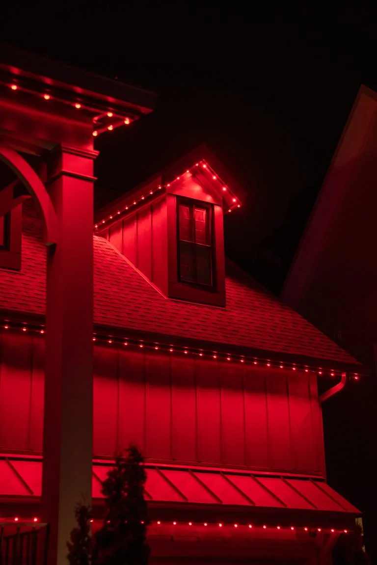 A house is illuminated with bright red lights, creating a dramatic nighttime effect