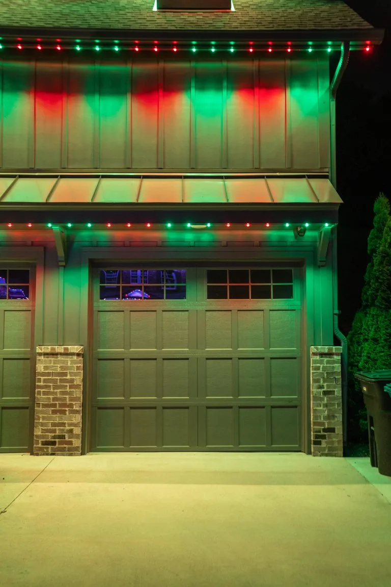 Colored holiday lights illuminate a garage facade at night