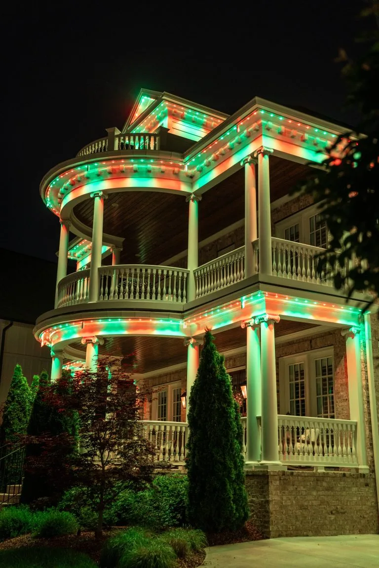 A beautifully lit house showcases green and red decorations against a night sky