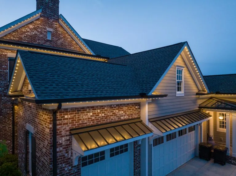 Twinkling lights outline a modern home at twilight, creating a warm ambiance