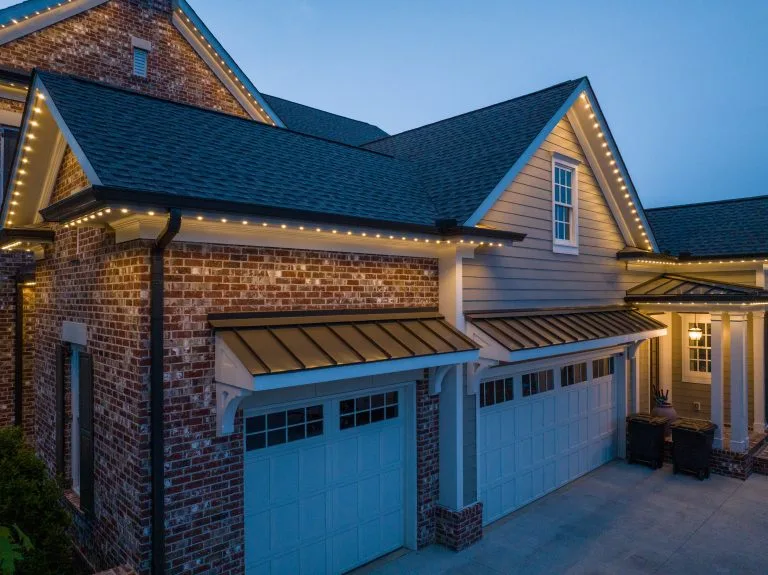A beautifully lit suburban house showcases a blend of brick and siding architecture at twilight
