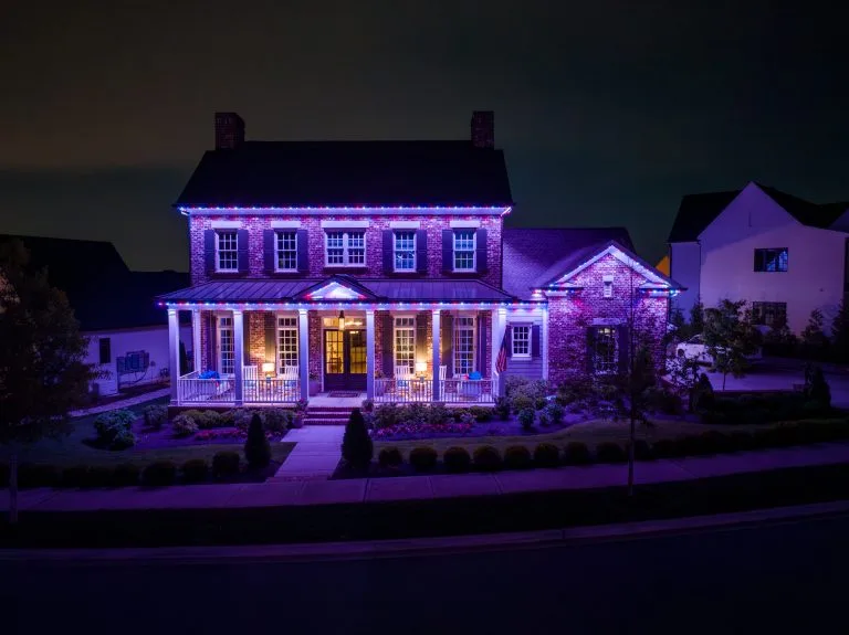 A beautifully lit house adorned with colorful lights glows in the evening