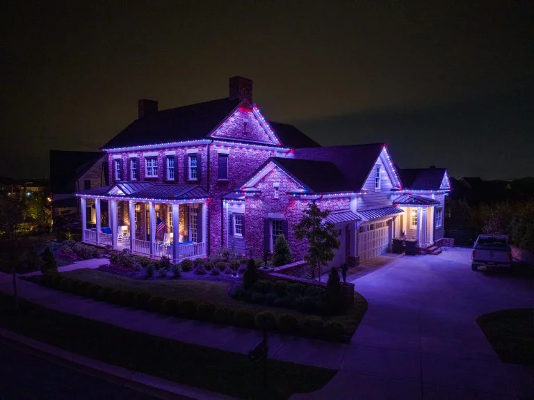 A beautifully illuminated house shines with colorful lights against a dark sky