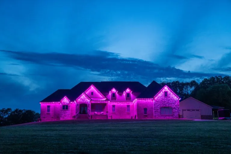 A large house is illuminated with vibrant pink lights against a twilight sky