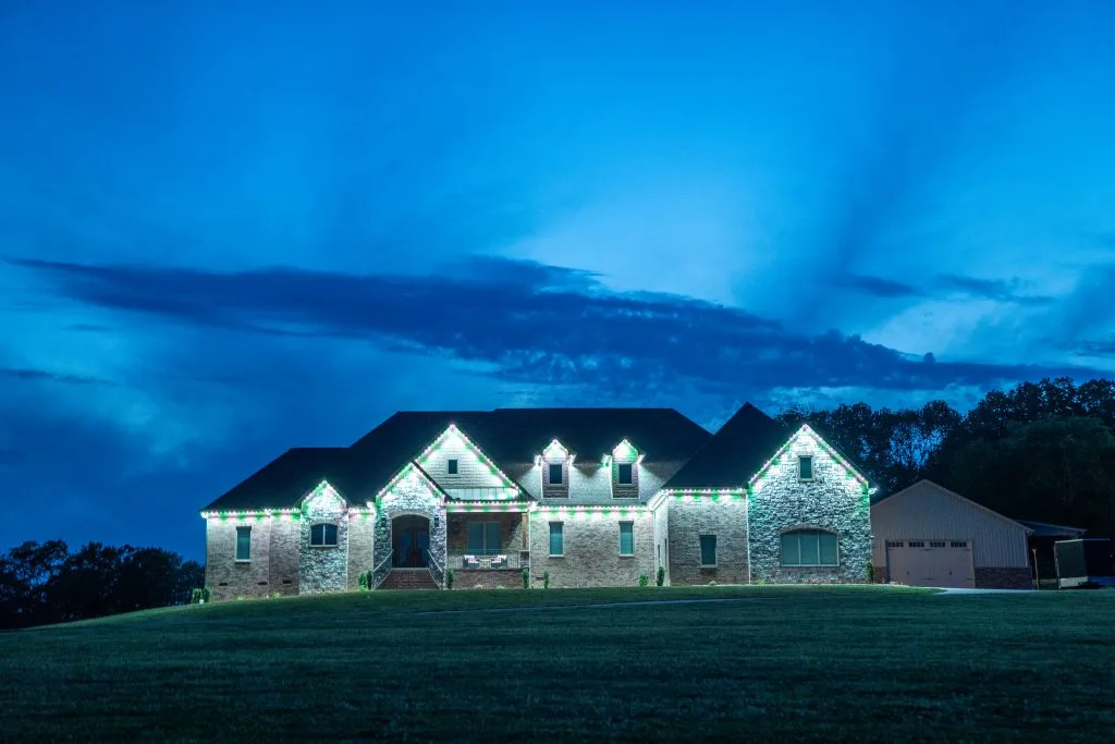 A beautifully lit stone house glows under a twilight sky filled with clouds