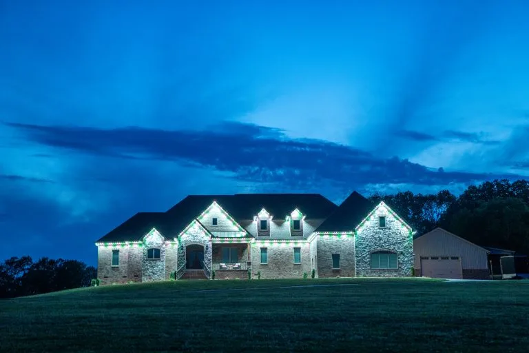 A beautifully lit stone house glows under a twilight sky filled with clouds