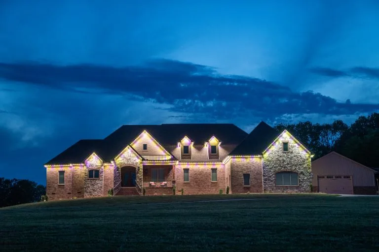 A beautifully lit house stands against a twilight sky, surrounded by dark clouds