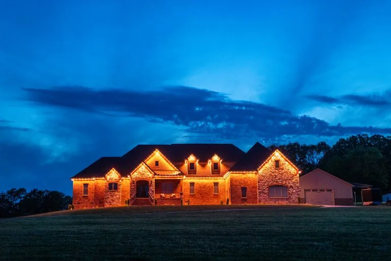 A beautifully lit stone house glows under a vibrant twilight sky