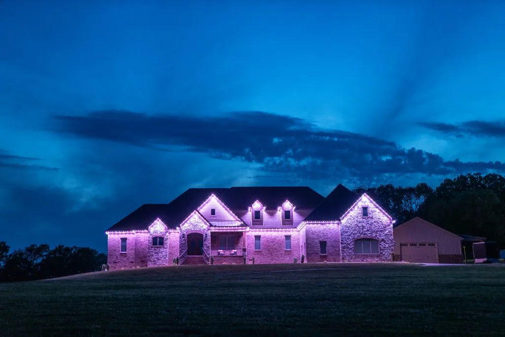 A charming house is illuminated with purple lights under a dramatic blue sky