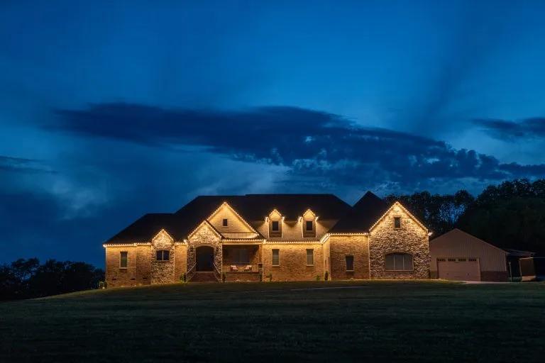 A beautifully illuminated stone house stands against a twilight sky