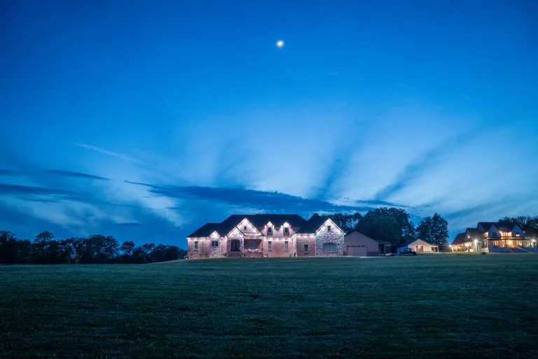 A beautifully lit house stands against a twilight sky filled with subtle clouds
