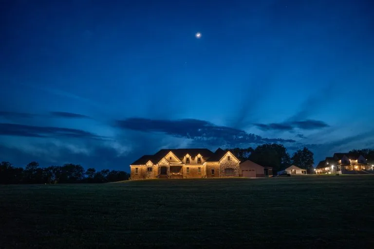 A beautifully illuminated house stands under a twilight sky with scattered clouds