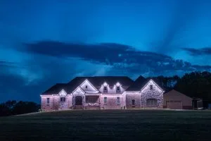 A well-lit house stands against a dramatic twilight sky
