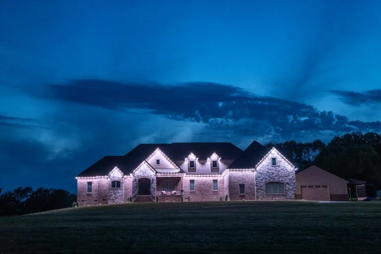 A beautifully illuminated house stands against a dramatic twilight sky