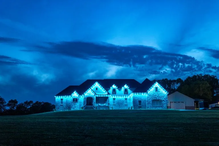 A large house illuminated with blue lights against a twilight sky