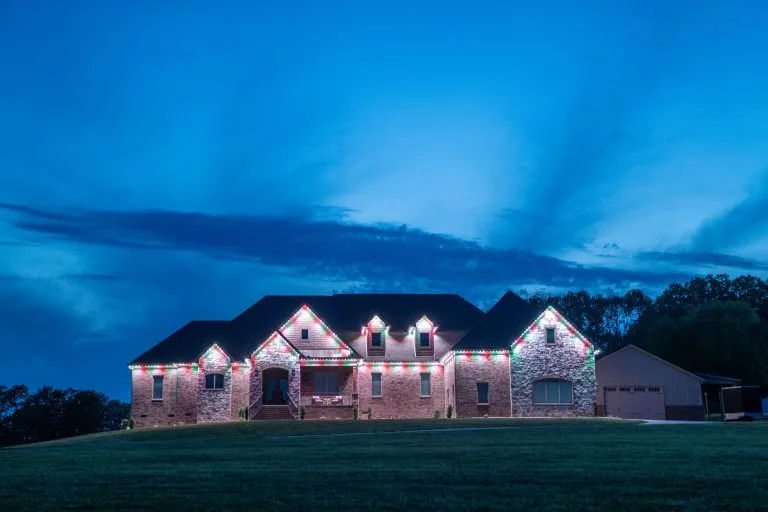A beautifully decorated house is illuminated with colorful lights against a twilight sky