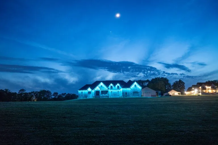 A large house illuminated with blue lights under a twilight sky