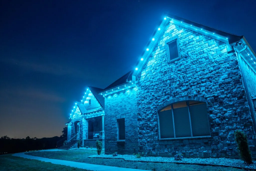 Permanent Christmas lights near Buckhead Atlanta illuminate a stone house with a calming blue glow at night